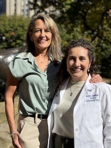 Two women, one in a lab coat, pose for camera